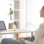 Femme assise devant son PC qui fait une pause pour évacuer le stress