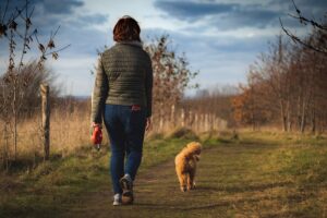 Eine Frau und ihr Hund gehen einen Weg in der Natur, Hund, Spazieren gehen, Bewegung, Natur